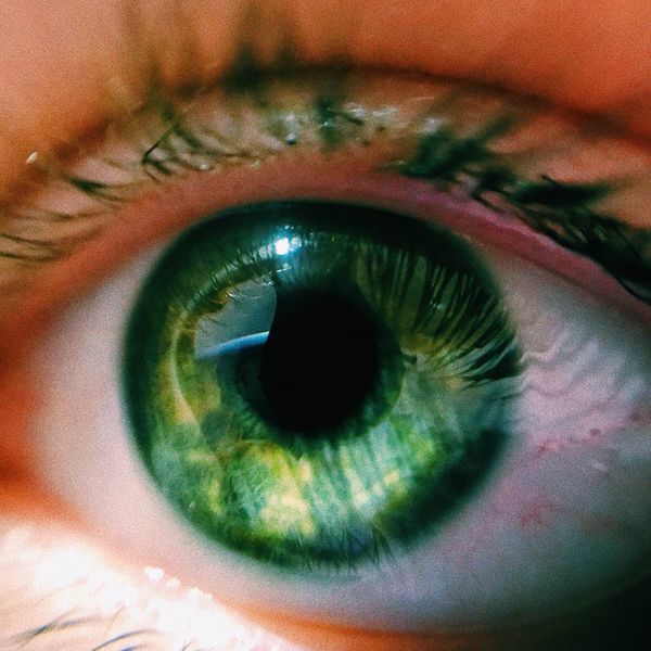Macro shot of a human eye with neon green reflection.